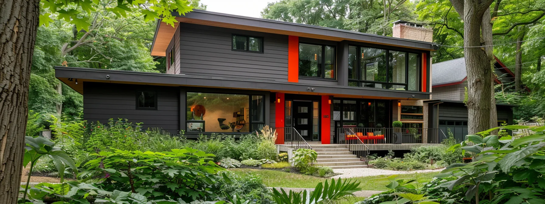 a beautiful, modern home with sleek gray siding and bright red accents, perfectly complementing the lush green landscaping surrounding it.