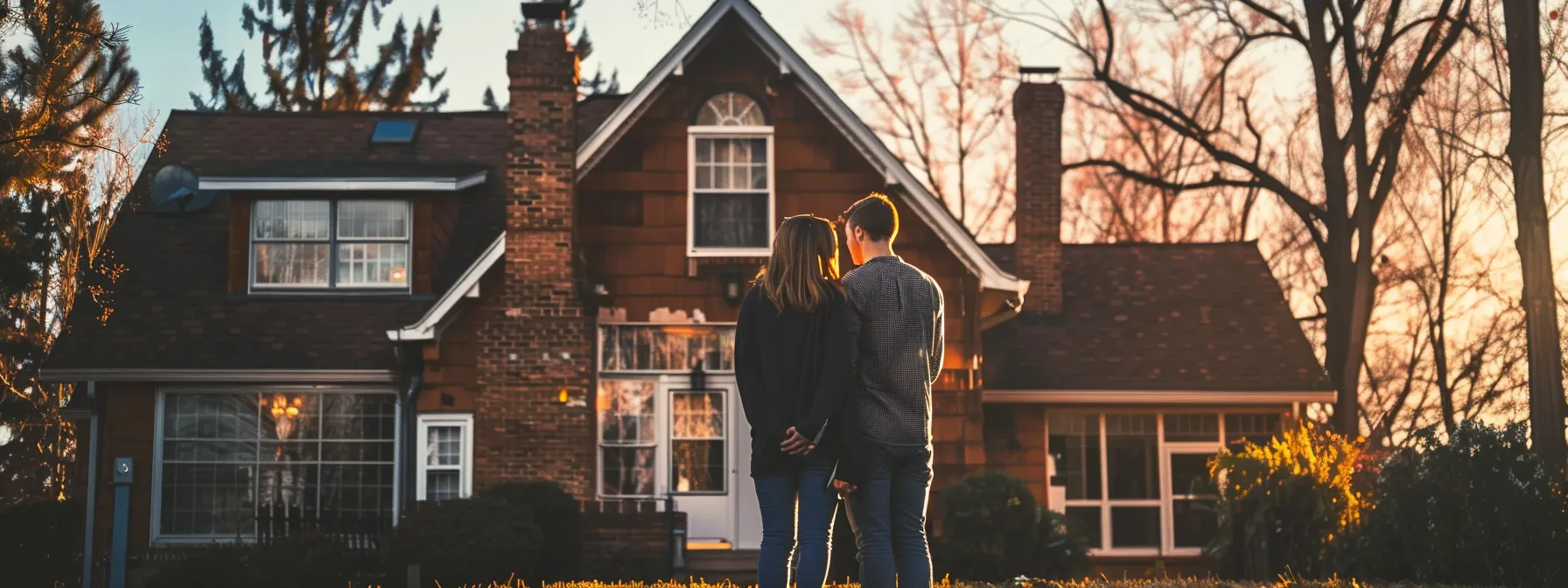 a young couple standing in front of a charming house, contemplating the pros and cons of buying a home at a young age.